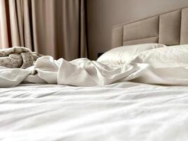 leeren Bett nach ein Nacht von Schlafen. gestreift Weiß Satin- Bett Leinen. Chaos auf Bett. skandinavisch Innere foto
