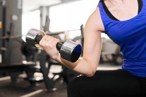 Hand von ein Frau durchführen Übung mit Hantel im das Fitnessstudio foto