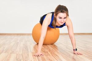 jung Frau ist Ausbildung durch tun drücken oben mit Yoga Ball im Fitnessstudio foto