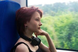 Mädchen Fahrten auf ein Pendler Zug und sieht aus aus das Fenster beim ein natürlich Landschaft verschwommen im Bewegung foto