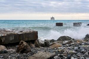 Strand mit Ruinen von industriell Strukturen und wackelig Aquakultur Vorposten weit aus zu Meer foto