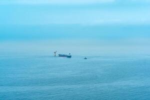 nebelig Seelandschaft mit ein Tanker in der Nähe von ein Öl Terminal gelegen weit aus zu Meer foto