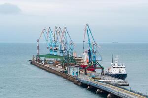 Ladung Liegeplatz mit Hafen Kräne und festgemacht Schiffe gegen das Hintergrund von das öffnen Meer foto