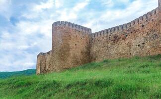 Mauer von ein mittelalterlich Festung über ein Wall bewachsen mit Gras gegen das Hügel und Himmel, Naryn-Kala Zitadelle im derbent foto