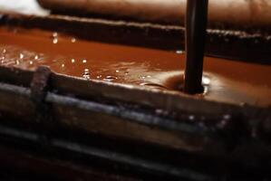 geschmolzen Schokolade gegossen in ein Tablett im ein Süßwaren Fabrik, Nahansicht foto