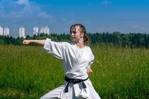 Teen Mädchen üben Karate Kata draußen im kiba-dachi Haltung foto