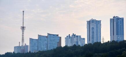 Morgen Stadtbild gegen das Himmel, mehrstöckig Wohn Gebäude und ein Fernseher Turm auf das oben von das Hügel foto