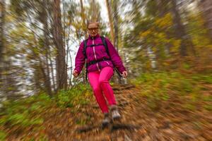 Frau Reisender sinkt ab von ein Hügel im das Herbst Wald, radial verwischen Hintergrund foto