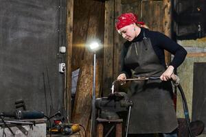 weiblich Handwerker Prozesse ein Metall Kunstwerk mit ein Schweißen Maschine foto