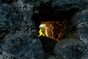 Loch im ein Stein Mauer durch welche das draußen Welt ist sichtbar foto