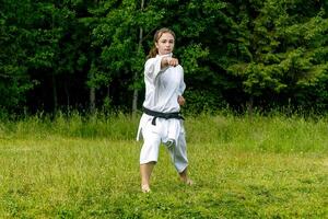 Teenager Mädchen Ausbildung Karate Kata draußen, führt aus schlagen seiken Chudan Tsuki foto