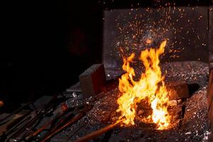 Schmied Ofen mit Verbrennung Feuer und Schmieden Werkzeuge Lügen in der Nähe foto