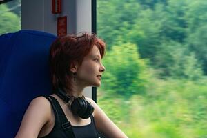 Mädchen Fahrten ein Zug draußen das Stadt und sieht aus aus das Fenster beim ein natürlich Landschaft verschwommen im Bewegung foto