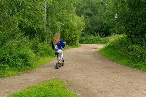 jung Frau Fahrten ein elektrisch Roller entlang das Pfad im das Park foto