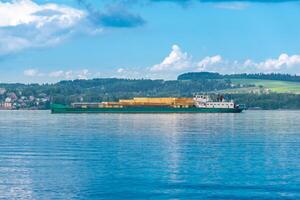 Ladung Schiff geladen mit Holz folgt ein breit Fluss auf ein sonnig Tag foto