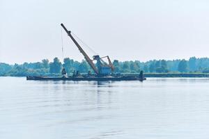 Ausbaggern Boot ist Arbeiten zu vertiefen das Fahrrinne auf das Fluss foto