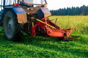 Traktor mit ein montiert Mäher mäht Wiese forbs foto