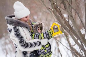 Mutter und Sohn im ein Winter Park Futter Vögel mit ein Feeder foto