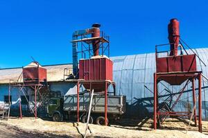 Bunker Silos zum Wird geladen Sägespäne Nächster zu das Halle, welche Häuser das Holzbearbeitung Industrie foto