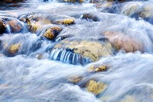 Kaskade von Wasserfälle von ein Berg Fluss unter das Felsbrocken, das Wasser ist verschwommen im Bewegung foto