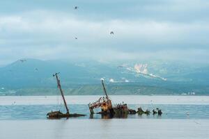 Schiffswrack gegen das Hintergrund von ein Meer Bucht mit nebelig Berge im das Hintergrund foto