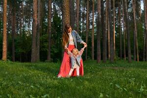 Frau mit wenig Tochter tanzen auf das Rasen im das Park foto