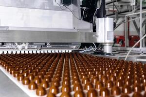 Schokolade Belag auf das Förderer von ein Süßwaren Fabrik Nahansicht foto
