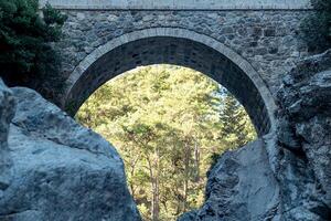 Bogen von uralt römisch Brücke Über ein Berg Fluss im das kesme bogazi Schlucht, Truthahn foto