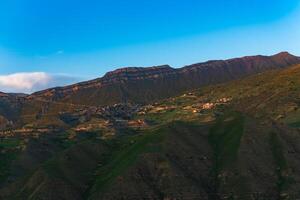 Berg Landschaft mit ein Dorf auf ein Steigung unter ein enorm felsig Grat, Chokh im Dagestan foto