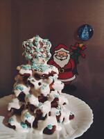 ein Dessert gemacht von Weihnachten Kekse gefaltet in ein Weihnachten Baum, bestreut mit pulverisiert Sahne und dekoriert mit klein Schneeflocken foto