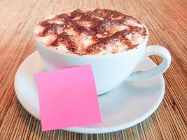 klebrig Hinweis mit heiß Schokolade Tasse auf hölzern Schreibtisch. foto