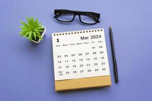 März 2024 Schreibtisch Kalender auf Blau Hintergrund. foto