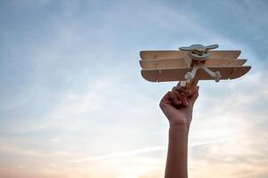 Kind halten ein hölzern Flugzeug Modell- hoch im das Himmel foto