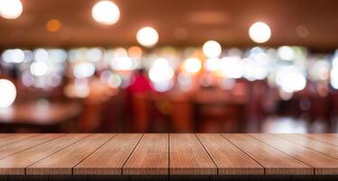 leeren hölzern Tabelle oben mit Beleuchtung Bokeh auf verwischen Restaurant Hintergrund. foto