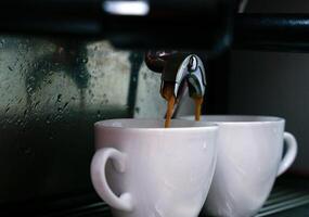 Kaffee ist gegossen von das Kaffee Maschine in Tassen. Fachmann Vorbereitung von natürlich Kaffee. Nahansicht. selektiv Fokus. foto