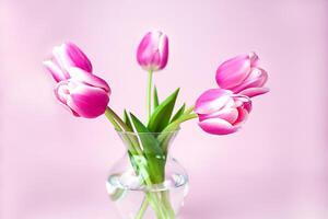 Rosa Tulpen Strauß im Glas Vase auf Rosa Hintergrund. Nahansicht. foto