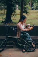 glücklich jung asiatisch Frau während Reiten ein Fahrrad im ein Stadt Park. sie lächelte mit das Fahrrad von Transport. ökologisch freundlich Konzept. foto