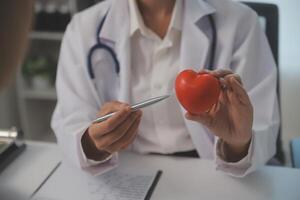 Hände von Arzt Frau halten rot Herz, zeigen Symbol von Liebe, Mensch Unterstützung zu geduldig, fördern medizinisch Versicherung, früh Untersuchung zum Gesundheitspflege, Kardiologe Hilfe. schließen oben von Objekt foto