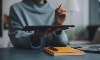 jung attraktiv weiblich Manager Arbeiten auf Digital Tablette während Stehen im modern Büro. zuversichtlich Geschäft Experte. attraktiv jung lächelnd Frau im Clever beiläufig tragen halten Digital Tablette foto