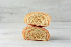 Schnitt im Hälfte Croissant mit Innerhalb Textur und dünn knackig Schichten auf hölzern Tisch. foto