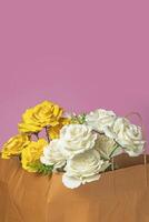 Strauß von Weiß und Gelb Rosen im ein braun Papier Tasche auf ein Rosa Hintergrund. Valentinstag Tag Konzept. foto