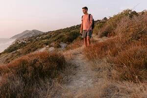 Wanderer Mann Gehen auf Ozean Küste mit warm Sonne Licht. foto