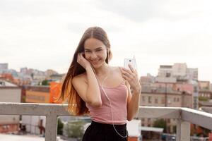 jung Frau mit Kopfhörer baumeln auf ihr Handy, Mobiltelefon Telefon foto