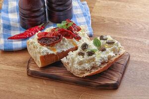 Bruschetta mit Weichkäse, Kapern und Tomate foto