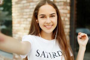 charmant jung Dame ist Herstellung Selfie auf ein Kamera foto