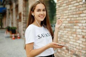 jung Frau mit Kopfhörer baumeln auf ihr Handy, Mobiltelefon Telefon foto