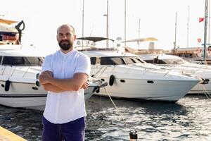 Foto von gut aussehend Mann mit Luxus Yacht im Hafen