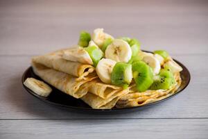 gekocht dünn Pfannkuchen mit Bananen und Kiwi foto