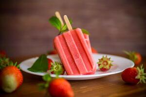 hausgemacht Erdbeere Eis Sahne auf ein Stock gemacht von frisch Erdbeeren im ein Teller foto