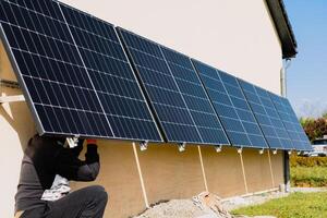 Solar- Paneele auf ein gut belichtet Mauer von ein Individuell Haus, Herstellung Ersparnisse folgenden das Energie Krise, Öko-Bürger Geste, Grün Energie foto